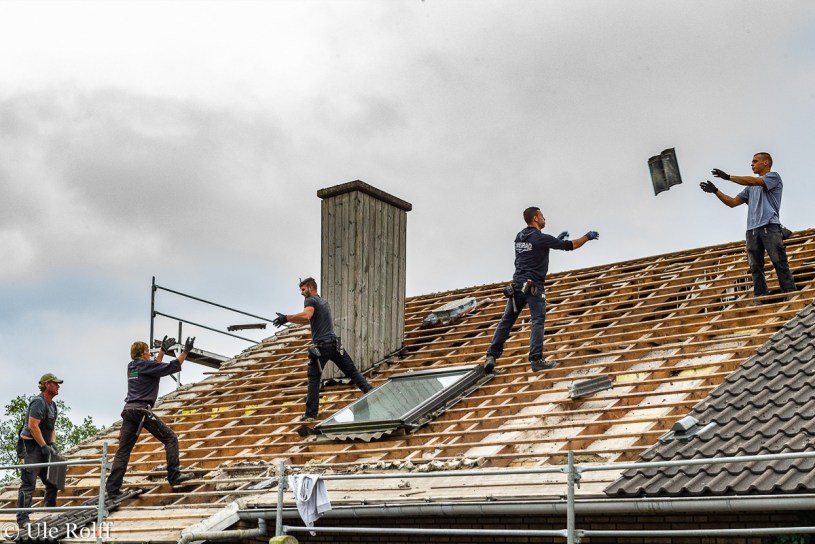 Dachdecker werfen Dachpfannen